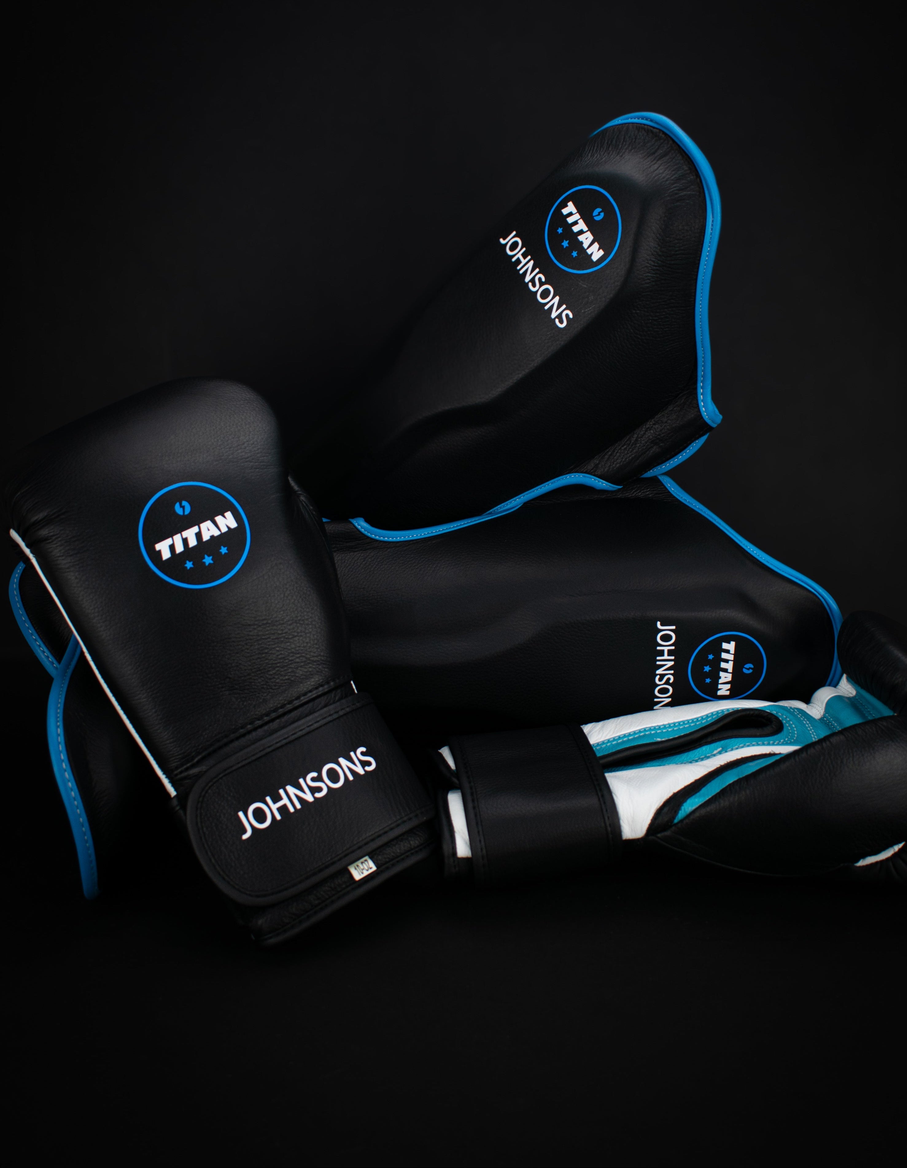 Black boxing gloves with blue accents and 'Johnson's' branding on a black background