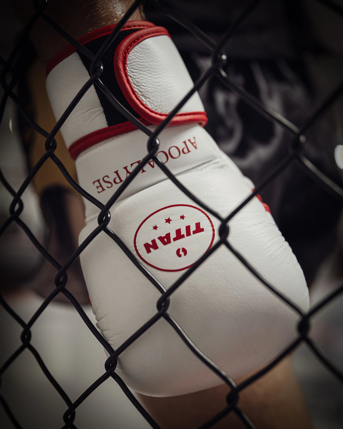 Bespoke white MMA glove with red trim and APOCALYPSE lettering, shot through the cage